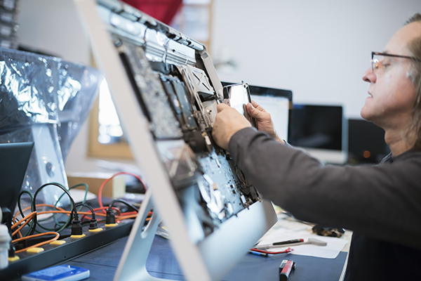 Computer Repair Shop,USA,Computer Repair Shop. A man with a computer monitor, taking it apart to mend it.